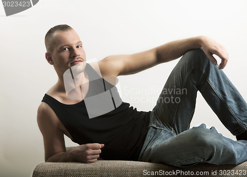 Image of man in muscle shirt lying on a sofa