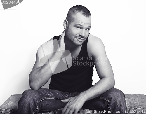 Image of young man sitting with hand on his head bw