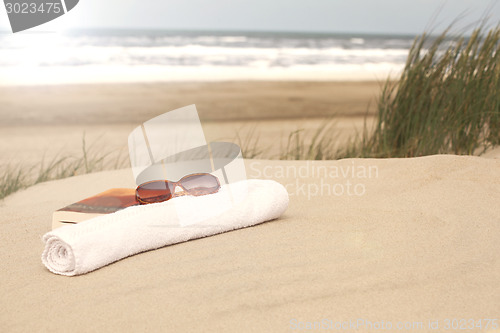 Image of Book sunglasses  towel on a beach