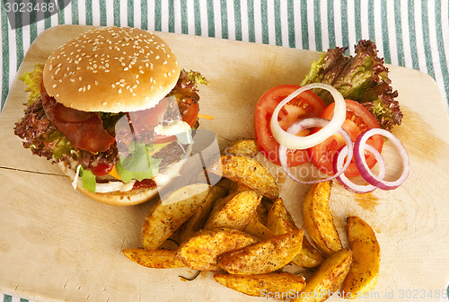 Image of burger with potato wedges on board