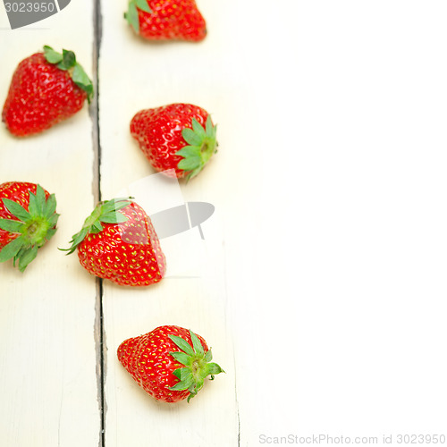Image of fresh organic strawberry over white wood