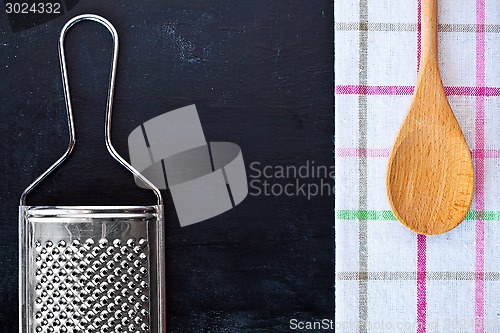 Image of wooden spoon, metal grater and tablecloth