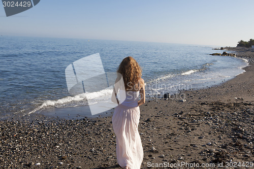 Image of young woman standing on beach