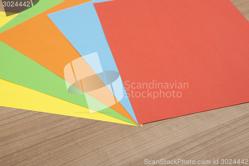 Image of colored paper on wooden background