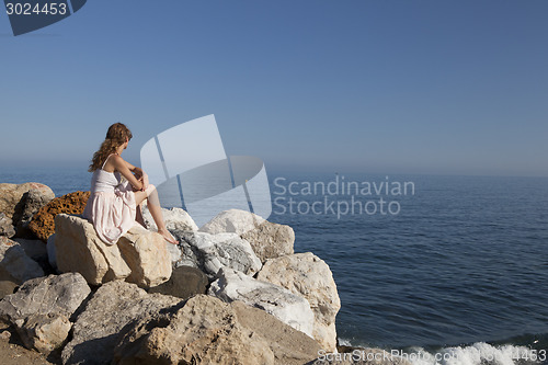 Image of at the sea young woman sitting on rock