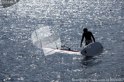 Image of kitesurfer stands in water