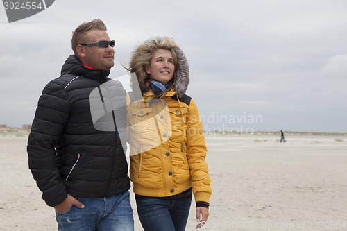 Image of Couple goes for a walk on the beach in autumn