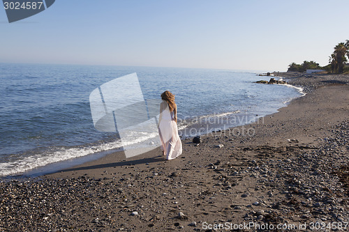 Image of young woman walking on the beach