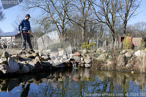 Image of man with garden hose on the pond