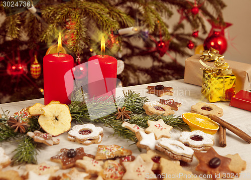 Image of many colorful biscuits and candles in front of christmas tree