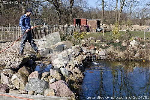 Image of man with hose on the garden pond