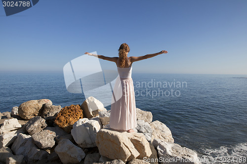 Image of young woman at the sea standing on rock