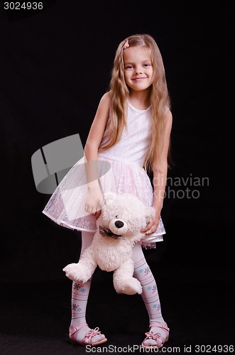 Image of Happy girl playing with teddy bear