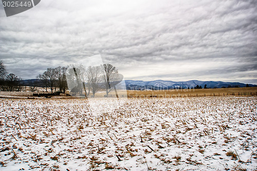 Image of snow covered farm field with mountains in background