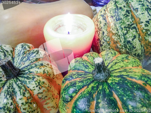Image of candle next to decorative pumpkins