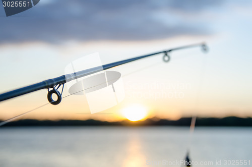 Image of fishing rod with lure at sunset over a lake