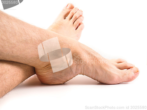 Image of Hairy legs and feet of male person resting towards white backgro