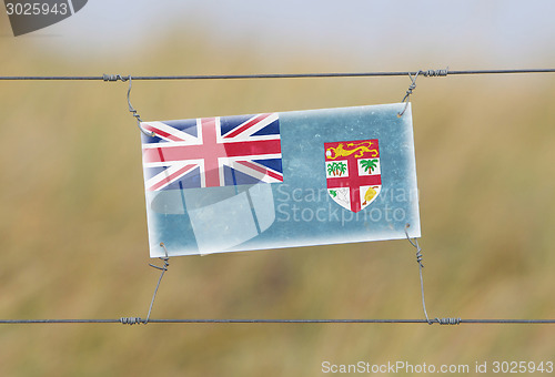 Image of Border fence - Old plastic sign with a flag