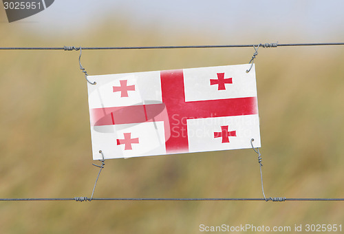 Image of Border fence - Old plastic sign with a flag