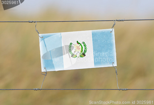 Image of Border fence - Old plastic sign with a flag