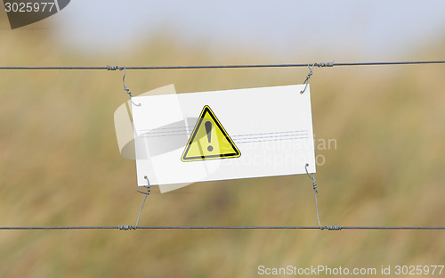 Image of Border fence - Old plastic sign with a flag