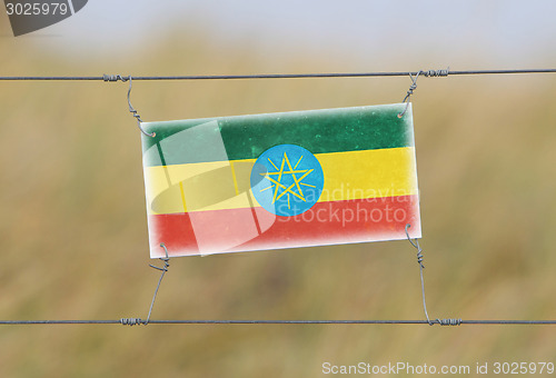 Image of Border fence - Old plastic sign with a flag