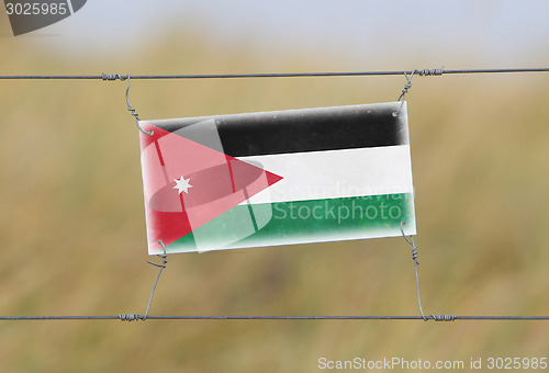 Image of Border fence - Old plastic sign with a flag