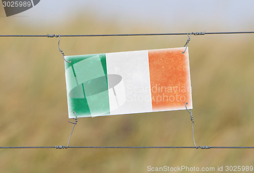 Image of Border fence - Old plastic sign with a flag