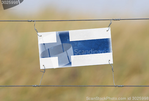 Image of Border fence - Old plastic sign with a flag