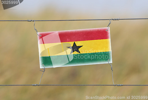 Image of Border fence - Old plastic sign with a flag