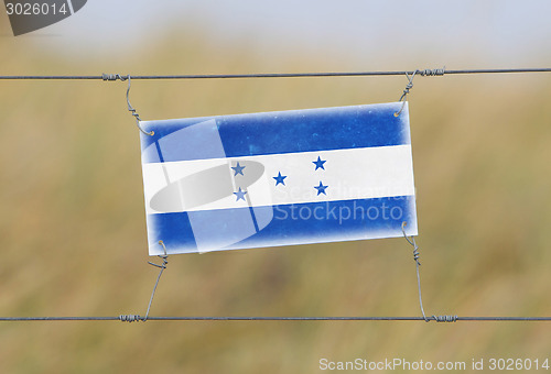 Image of Border fence - Old plastic sign with a flag