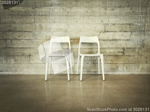 Image of White chairs near concrete wall