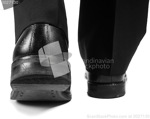 Image of Closeup of male suit walking away in black worn shoes towards wh