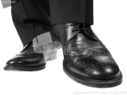 Image of Person in black suit and shoes lifting one foot towards white