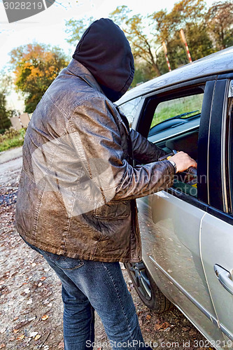 Image of Hooligan breaking into car