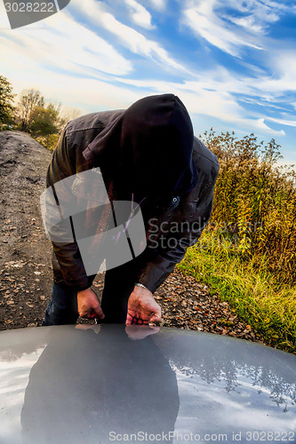 Image of Hooligan breaking into car