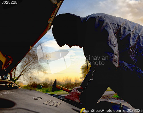 Image of Hooligan breaking into car