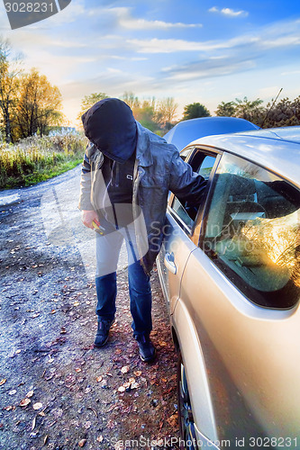 Image of Hooligan breaking into car