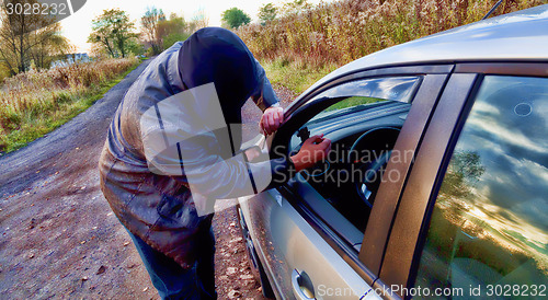 Image of Hooligan breaking into car