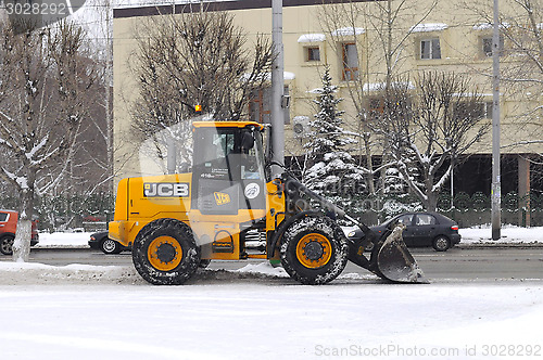 Image of The yellow bulldozer cleans snow on city streets.