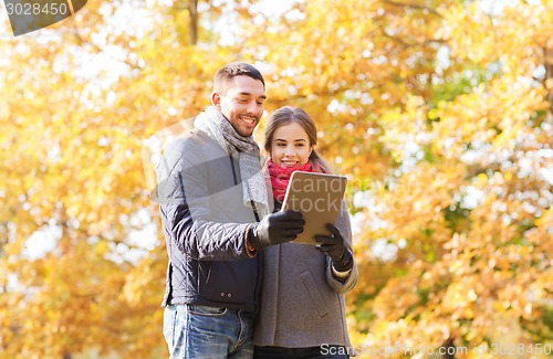 Image of smiling couple with tablet pc in autumn park