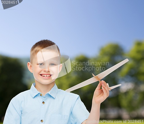 Image of smiling little boy holding a wooden airplane model