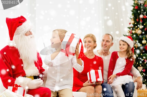 Image of smiling family with santa claus and gifts at home