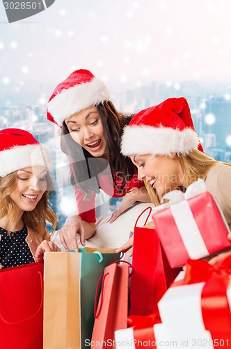 Image of smiling young women in santa hats with gifts