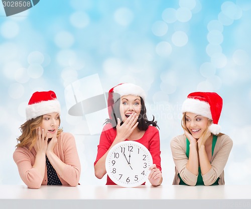 Image of smiling women in santa helper hats with clock