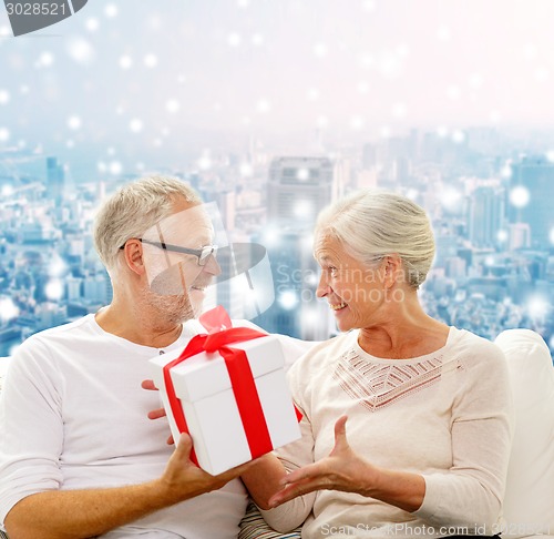 Image of happy senior couple with gift box at home