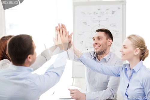 Image of happy business team giving high five in office