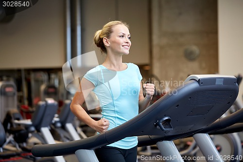 Image of smiling woman exercising on treadmill in gym