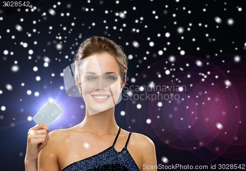 Image of smiling woman in evening dress holding credit card