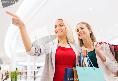 Image of happy young women with shopping bags in mall